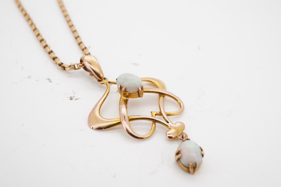 An Art Nouveau gold and opal pendant and chain, early 20th century, the pendant of sinuous design, set with two cabochon opals, to a gold belcher link chain necklace, chain length 45cm, stamped 15ct, pendant 4.7cm, stamp